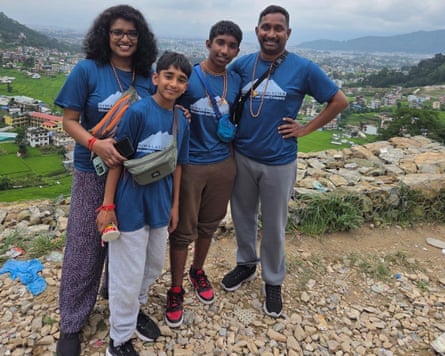 Four family members is blue T-shirts stand on a mountain smiling