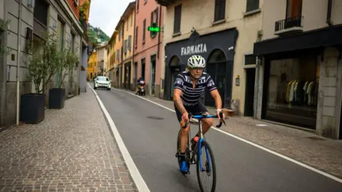 Getty Images A man rides a bike along street near Lake Como.