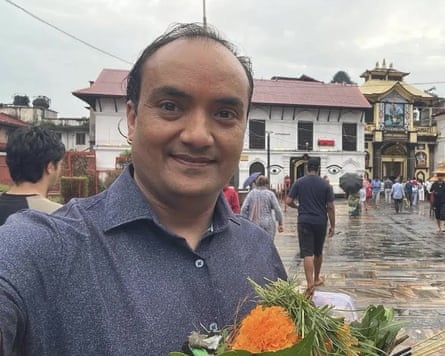 Narayan Panthi stands in front of a house holding flowers