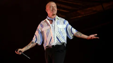 Getty Images Macklemore performing on stage with microphone in hand