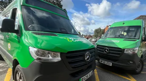 BBC Two green minibuses parked up at an angle next to each other. Both have Wiltshire Connect written across their bonnets.
