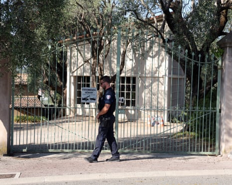 A police officer walks beside a large closed gate, with the museum building behind