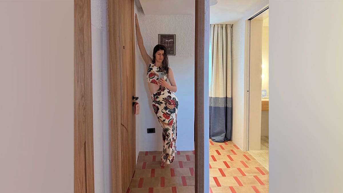 Alexandra Daddario takes a mirror selfie in a cream floral matching set with a waist cutout.