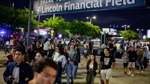 Reuters People walk in the evening towards the venue for the concert of pop star Ed Sheeran. A sign above them reads Lincoln Financial Field.