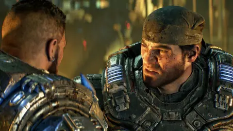 Xbox Game Studios Gears of War character Marcus Fenix wears a bandanna and heavy futuristic armour. The CGI character has a cropped beard and blood-spattered face and looks seriously at another of the game's characters, seen from behind.