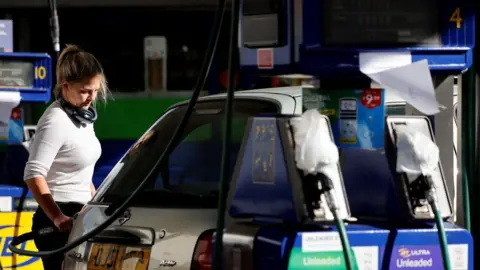 AFP via Getty Images A blonde woman fills her car up with diesel