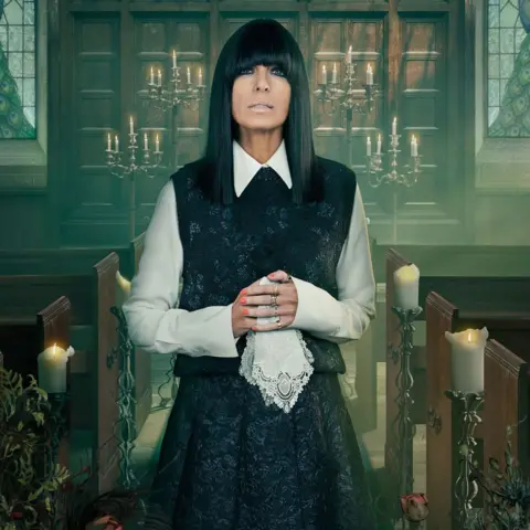 BBC/Studio Lambert/Cody Burridge/BBC Creative Claudia Winkleman in a white shirt, black sleeveless jumper and long black skirt; she's holding a white lace handkerchief