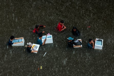 People wade through a flooded area during heavy rain in Bangkok.