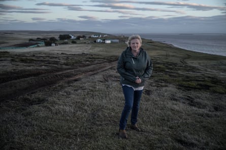 Dot Gould stands on a grassy hillside on Pebble Island, overlooking the settlement and sea