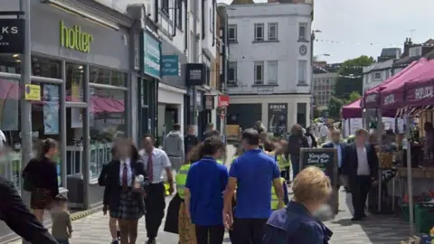 Google Businesses beside the market, before the fire, undamaged. People walking past